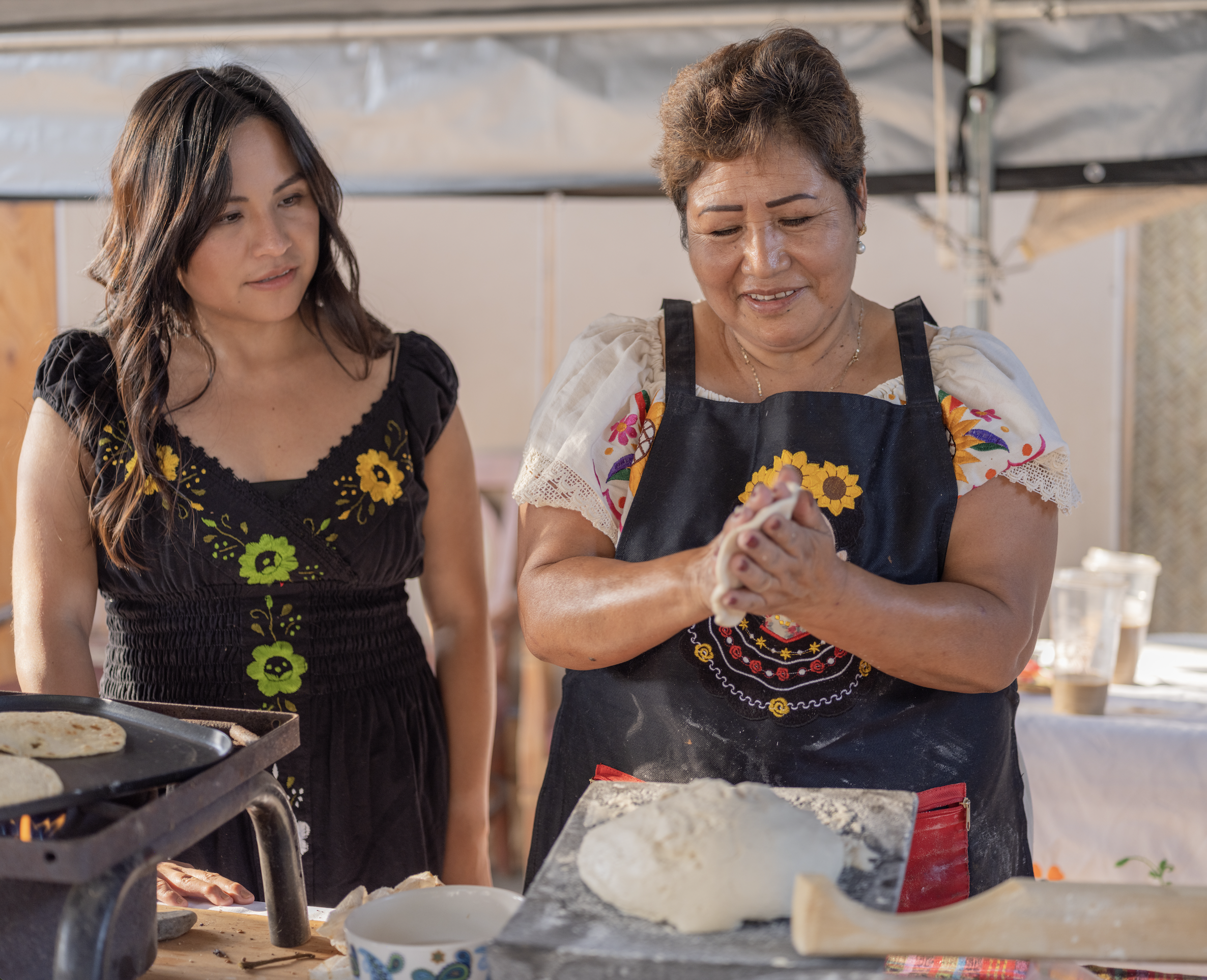 Image of two Indigenous women hand pressing tortilla dough