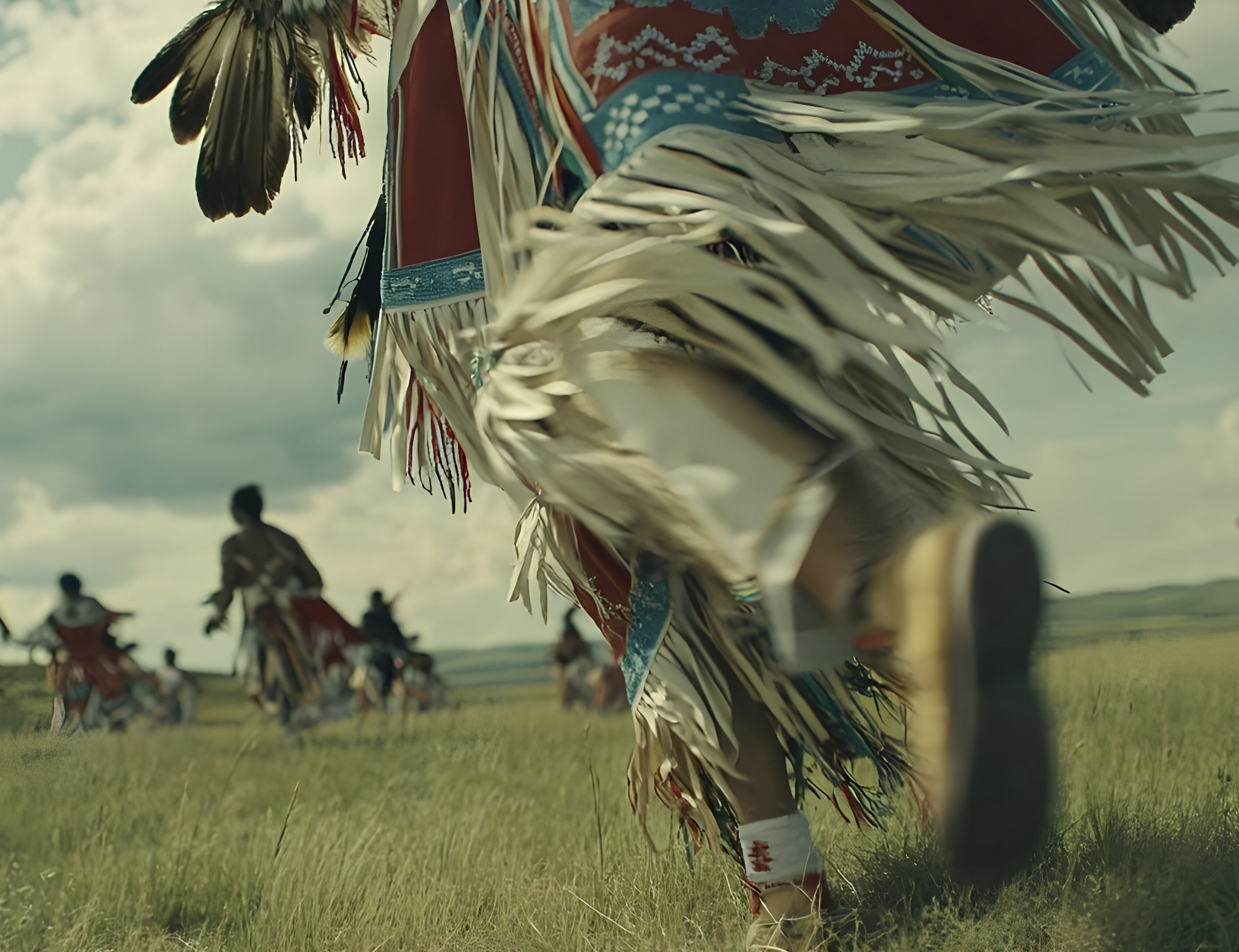 Image of someone in regalia dancing in field 