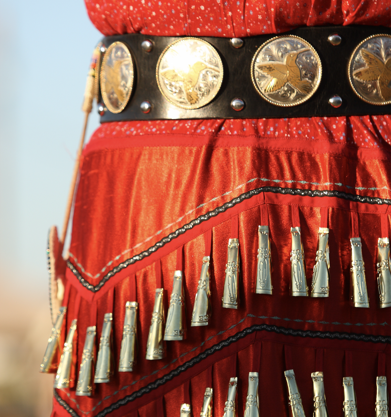 Cropped image of a red jingle dress regalia with conch belt 