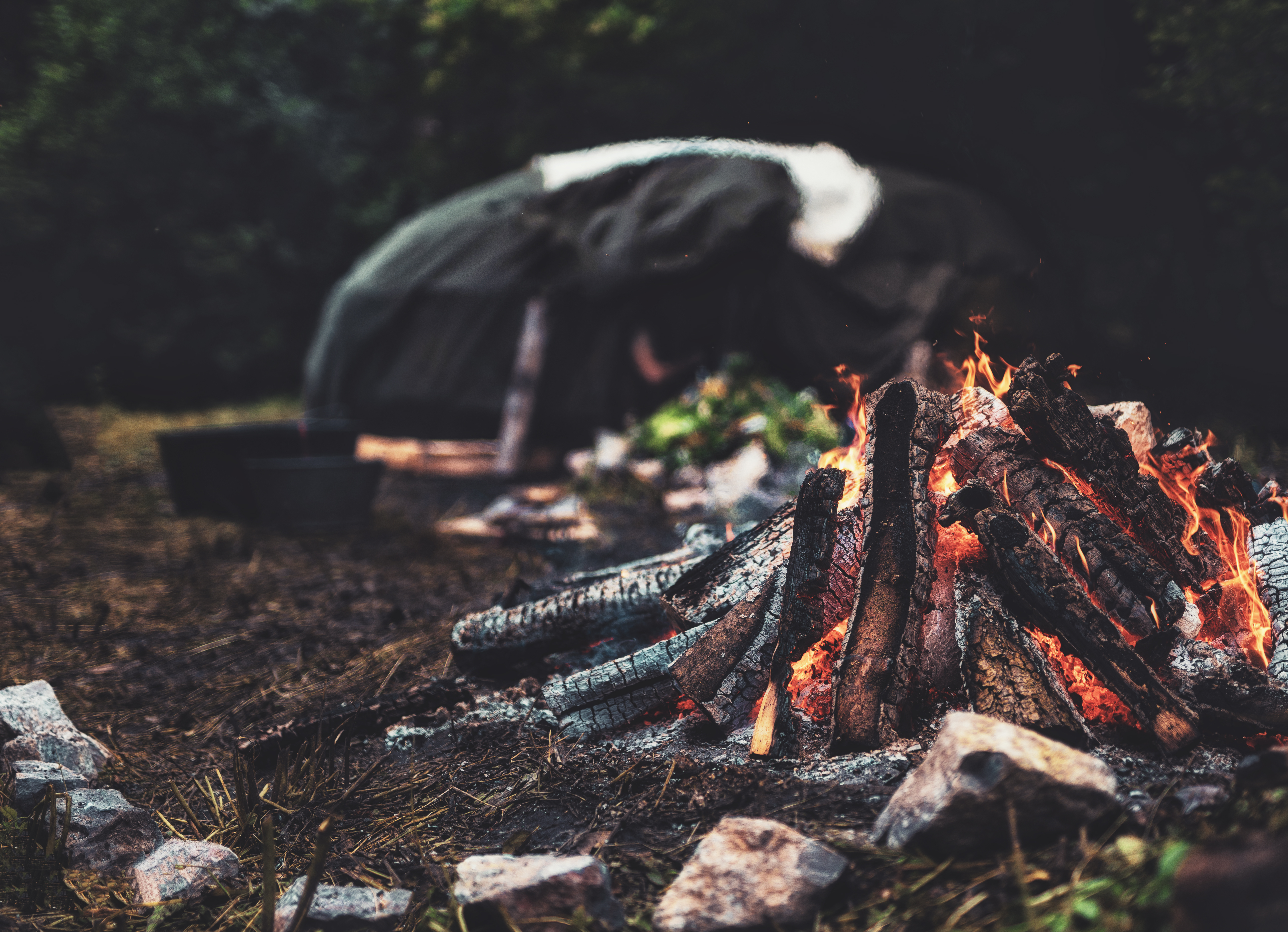 Image of fire with sweat lodge blurred in background