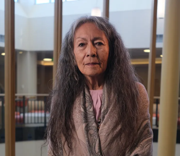 Portrait of Christina with long hair wearing a gray shawl in a well lit room
