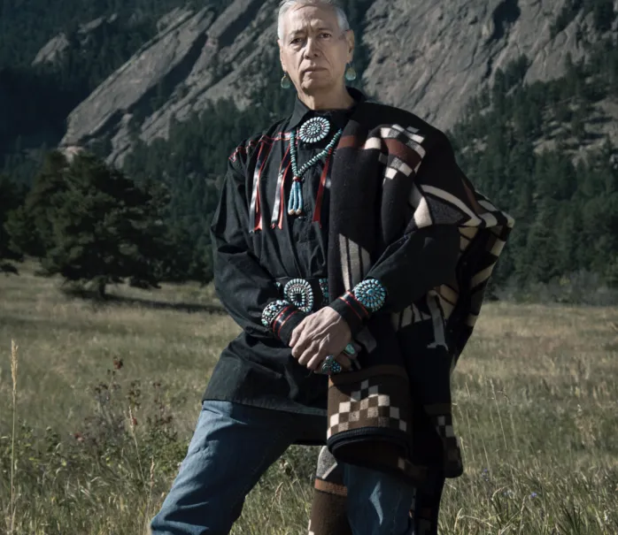 Photo of David Atekpatzin Young in traditional clothing at bottom of Flat Iron mountain range