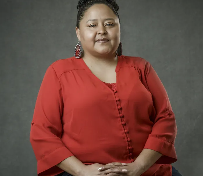 Portrait of a woman with her hair up and wearing a red shirt. 